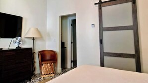 A hotel room with a bed, a dresser, a chair, a lamp, and a sliding door. - Lodges Combined Suite on the Mason Tx Square (Mason)
