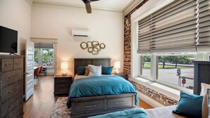 A bedroom with a bed, bedside tables, a TV, a dresser, and a window with blinds. - Drifter Suites Combo (Mason)