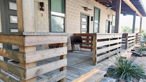 Une terrasse en bois avec un banc et une table, entourée d’une clôture rustique et de plantes.