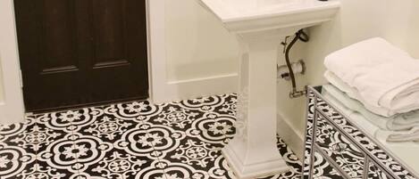 Une salle de bain avec un lavabo sur colonne blanc, un miroir et un porte-serviettes.