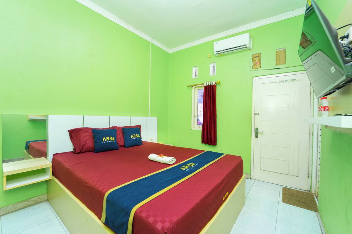 A room with a bed, a door, and an air conditioning unit on the wall.
