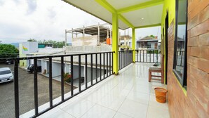A balcony with a tiled floor, a wooden chair, and a basket. - Hotel D2 By ARBA (Weleri)