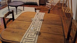 Een gezellige kamer met een houten eettafel, een bed met wit beddengoed en een hanglamp.