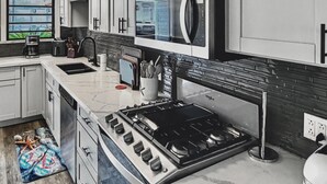 A modern kitchen with grey cabinets, a built-in microwave, a gas stove, and a coffee maker.