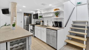 Eine moderne Küche mit weißen Schränken, Edelstahlgeräten und einer Holztreppe.
