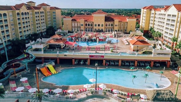 Un hotel con una piscina grande, toboganes de agua y varios balcones.