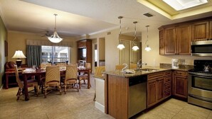 Una cocina moderna con armarios de madera, una isla central, electrodomésticos de acero inoxidable e iluminación colgante.
