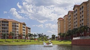 Un bote con forma de cisne en un lago, con un edificio de hotel al fondo.