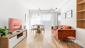 Un salon moderne avec un téléviseur à écran plat, des meubles en bois, une table de salle à manger ronde et un canapé.