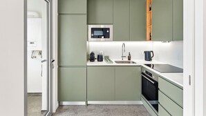 Une cuisine moderne avec des meubles de couleur verte, un four à micro-ondes, un évier et une cuisinière.