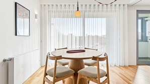 Un espace repas moderne avec une table ronde en bois, quatre chaises et un luminaire suspendu.