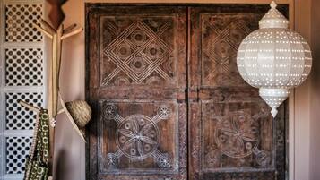 A wooden door with intricate carvings and a hanging white lantern.