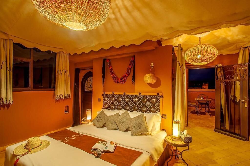 Habitación de hotel con una cama grande, un candelabro y vistas al exterior.