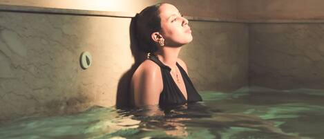 A person in a bathtub with a light source above.
