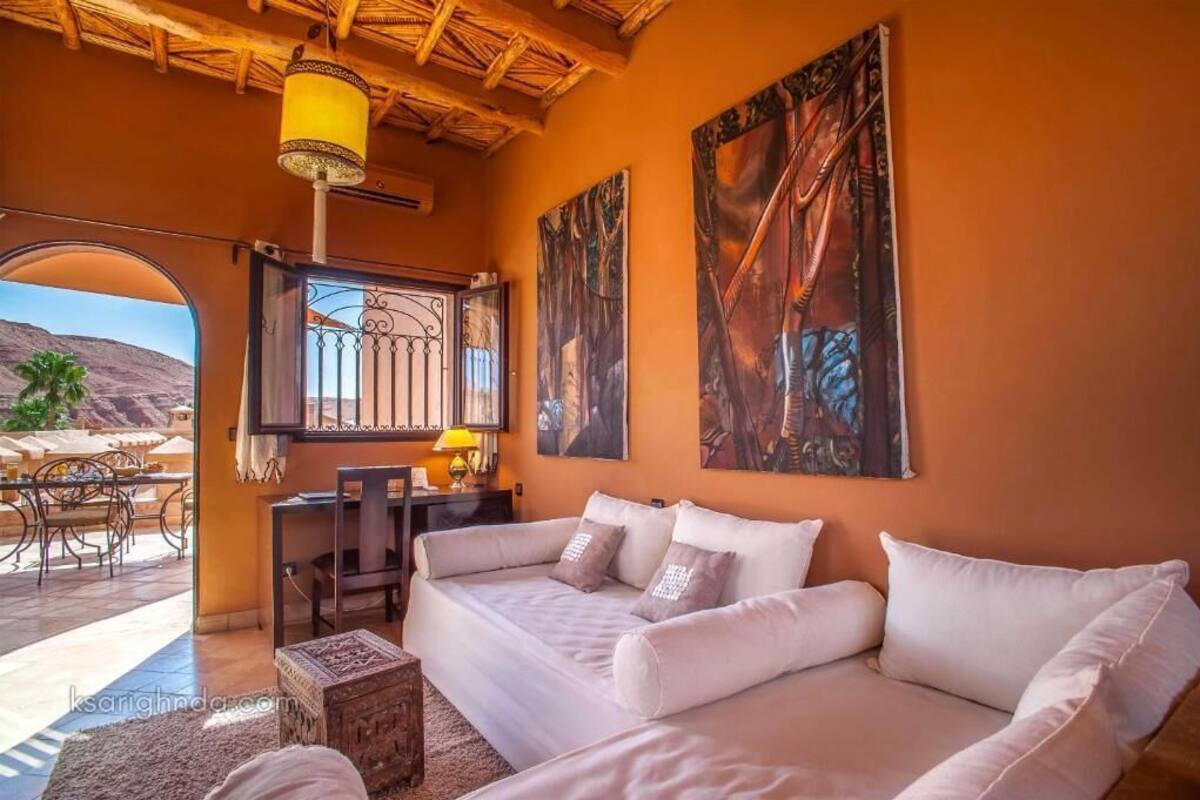 A cozy living room with a white sofa, a small table, and a window with a view of the desert landscape.