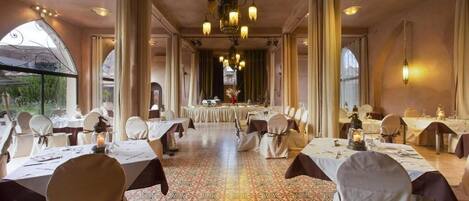 A banquet hall with round tables, chairs, and a patterned floor.