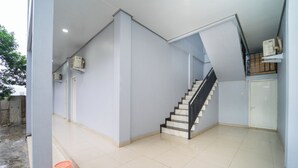 A clean, modern interior with a staircase, tiled floors, and air conditioning units. - Hotel Panorama Batang By ARBA (Banyuputih)