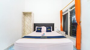 A neatly made bed with a white and blue bedspread, two pillows with 'ARBA' branding, and a blue and yellow bed runner. - Hotel Panorama Batang By ARBA (Banyuputih)