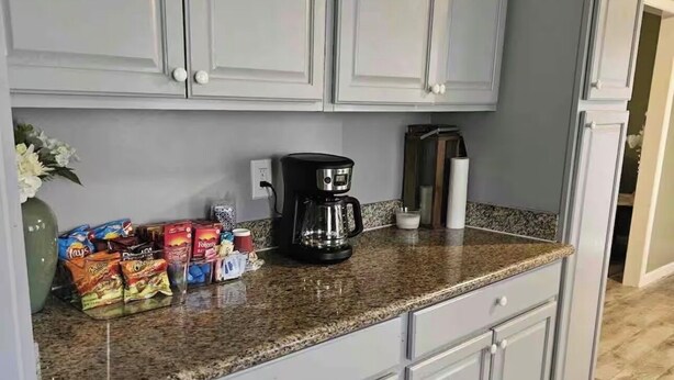 Eine Küche mit grauen Schränken, einer Arbeitsplatte aus Granit und einer Kaffeemaschine.