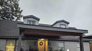 Ein zweistöckiges Haus mit überdachter Veranda, einer Haustür mit Weihnachtskranz und einer sternförmigen Dekoration.