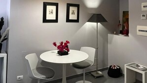 A modern dining area with a round table, two chairs, a pendant light, framed artwork, and a small side table. - ZUCCHELLI ROMAN RESIDENCE (Roma)
