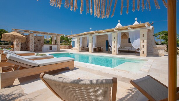 Ein Poolbereich mit Liegestühlen, einem Pool und einer überdachten Sitzgelegenheit mit Blick auf den Pool.