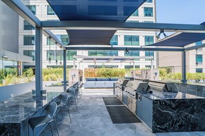 Eine Außenpatio mit Grill, Sitzgelegenheit und Blick auf das Gebäude im Hintergrund.