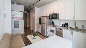 Une cuisine moderne avec des meubles blancs, des appareils en acier inoxydable et un îlot central.