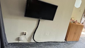 Een flatscreen televisie bevestigd aan een muur, met een kabel naar een stopcontact.