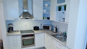 Een moderne keuken met witte kasten, roestvrijstalen apparatuur en een betegelde spatwand.