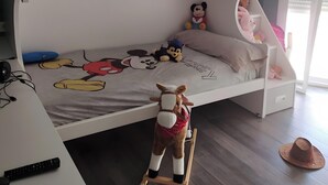A bunk bed with a Mickey Mouse themed bedspread, a desk with a computer and a remote control, and a window with blinds. - Holiday Home 'Alojamiento Patricia' with Mountain Views, Private Terrace and Wi-Fi (Igualeja)