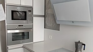 A modern kitchen with stainless steel appliances, white cabinetry, and a sleek countertop. - Holiday Home 'Alojamiento Patricia' with Mountain Views, Private Terrace and Wi-Fi (Igualeja)