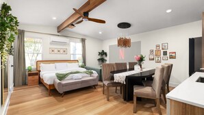 A modern bedroom with a bed, a dining table, and a ceiling fan. - Zen Den · Hot Tub · Cold Plunge · Movie Area (Austin)