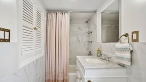 Een badkamer met een douche, een wastafel en een spiegel.
