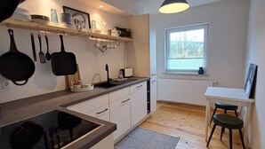 A compact kitchen with a built-in stove, white cabinets, and a window providing natural light. - Relaxing time out on the Weser dyke (Bremen)