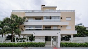 A multi-story residential building with a flat facade, balconies, and a sign indicating 'MARES DO SUL 1720.' - Apto c/ Churrasqueira a 400m da Praia MDR0104 (Florianópolis)