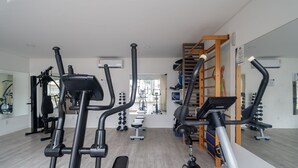 A gym with exercise equipment, a mirrored wall, and a view of the outside. - Apto c/ Churrasqueira a 400m da Praia MDR0104 (Florianópolis)