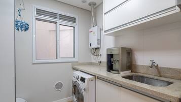 A compact kitchen with a built-in washing machine, a water heater, and a sink.
