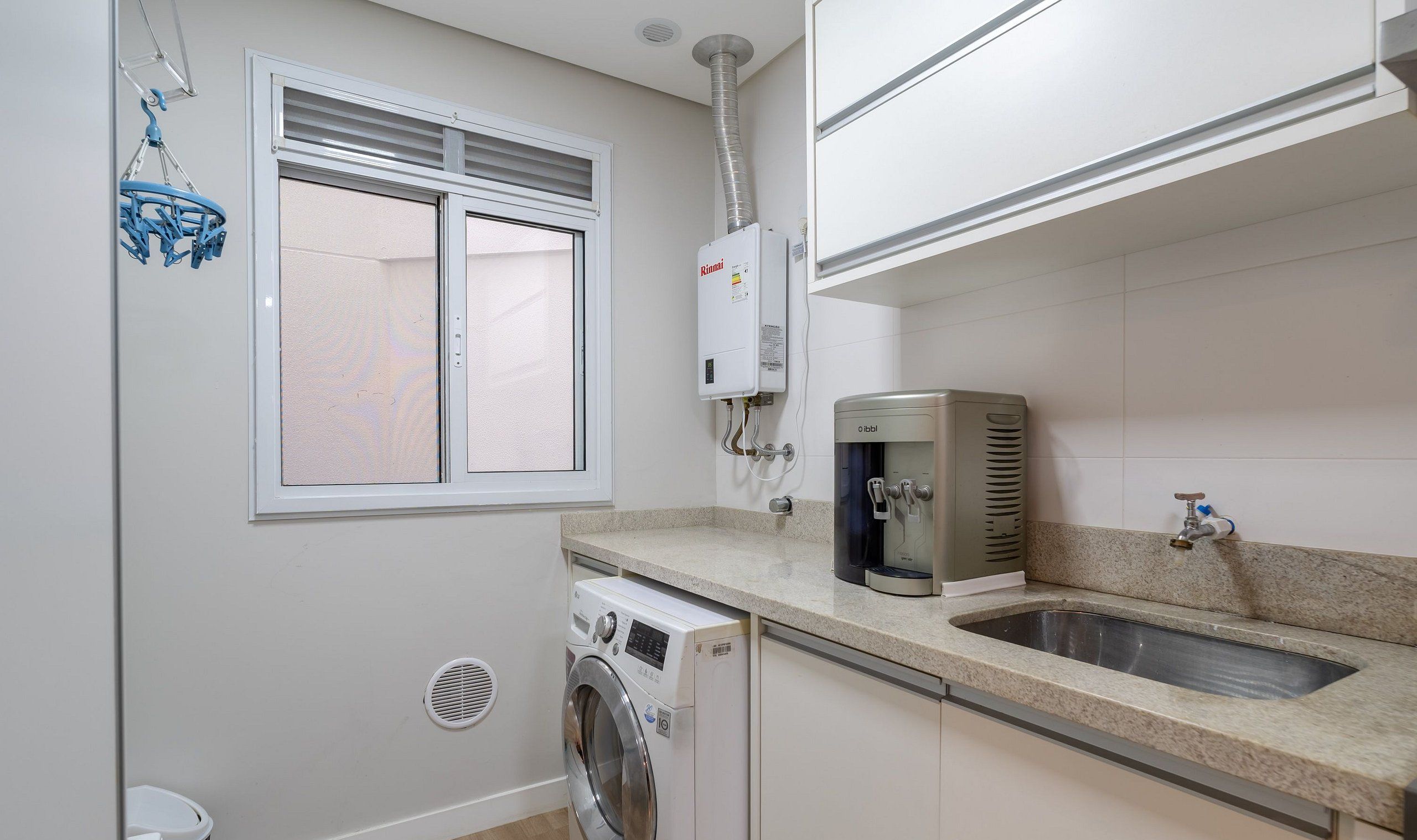 A compact kitchen with a built-in washing machine, a water heater, and a sink.