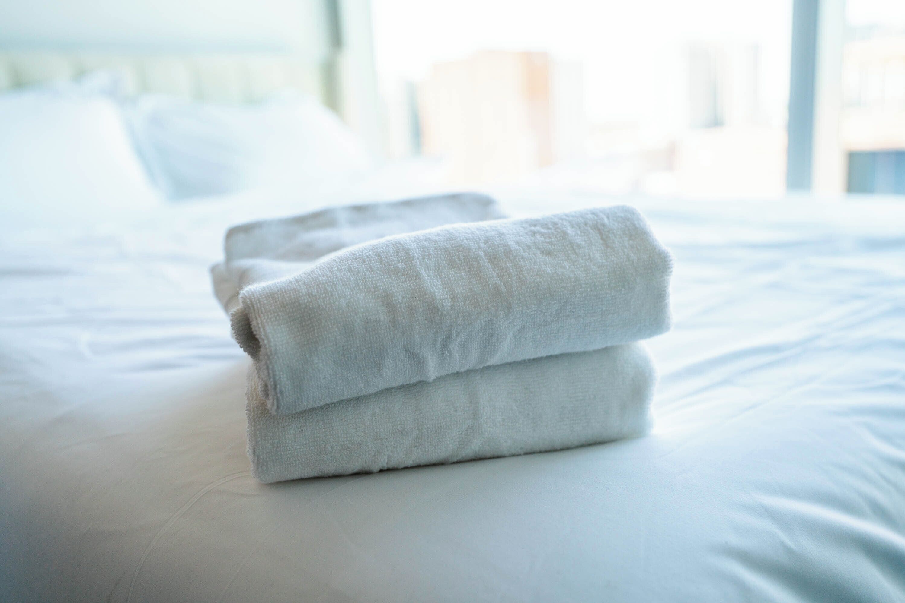 Una cama bien hecha con toallas blancas dobladas.