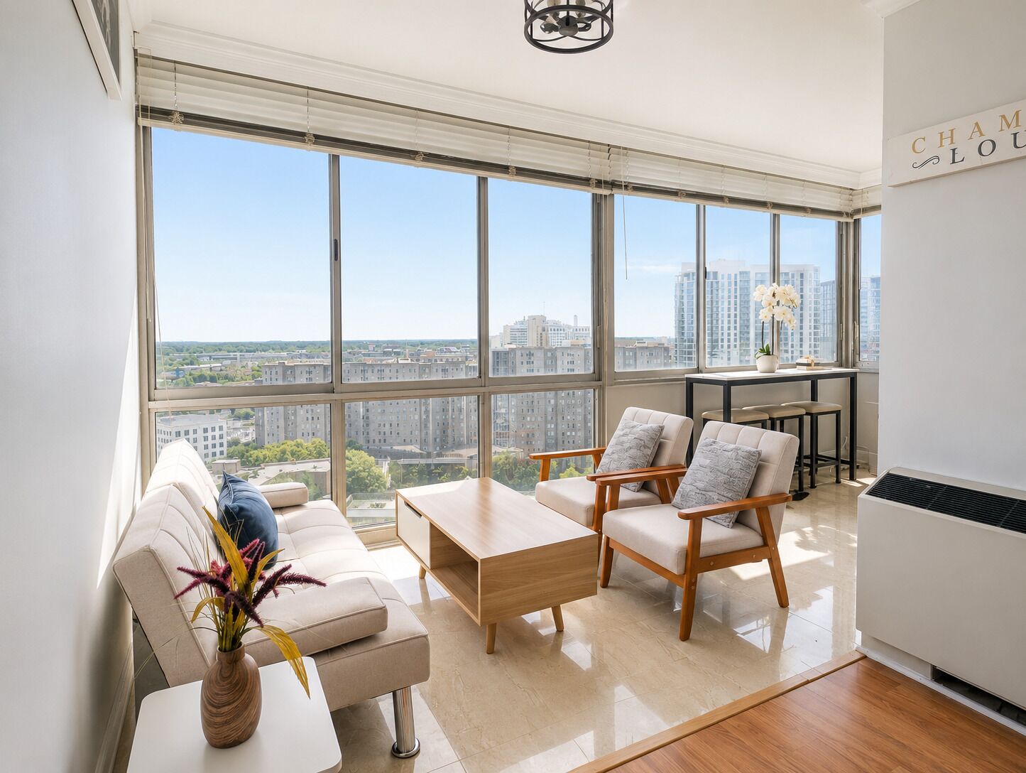 A modern living room with large windows, a sofa, two armchairs, a coffee table, and a small table with a vase.