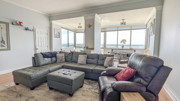 A spacious living room with a sectional sofa, ottoman, and a leather armchair. - The ATL Sky Suite High-Floor 3BR Downtown Penthouse Stunning City Views (Atlanta)