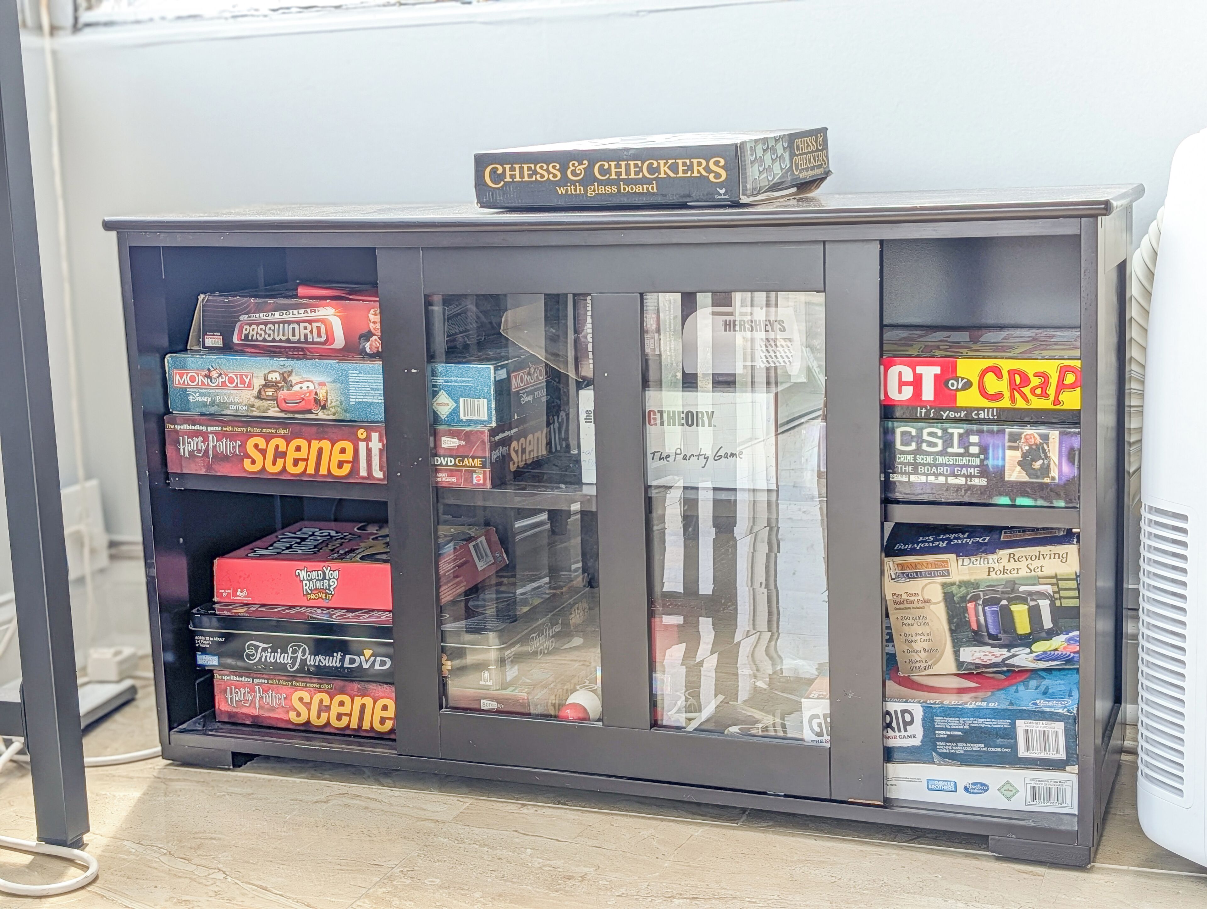 A game display cabinet with various board games and DVDs.