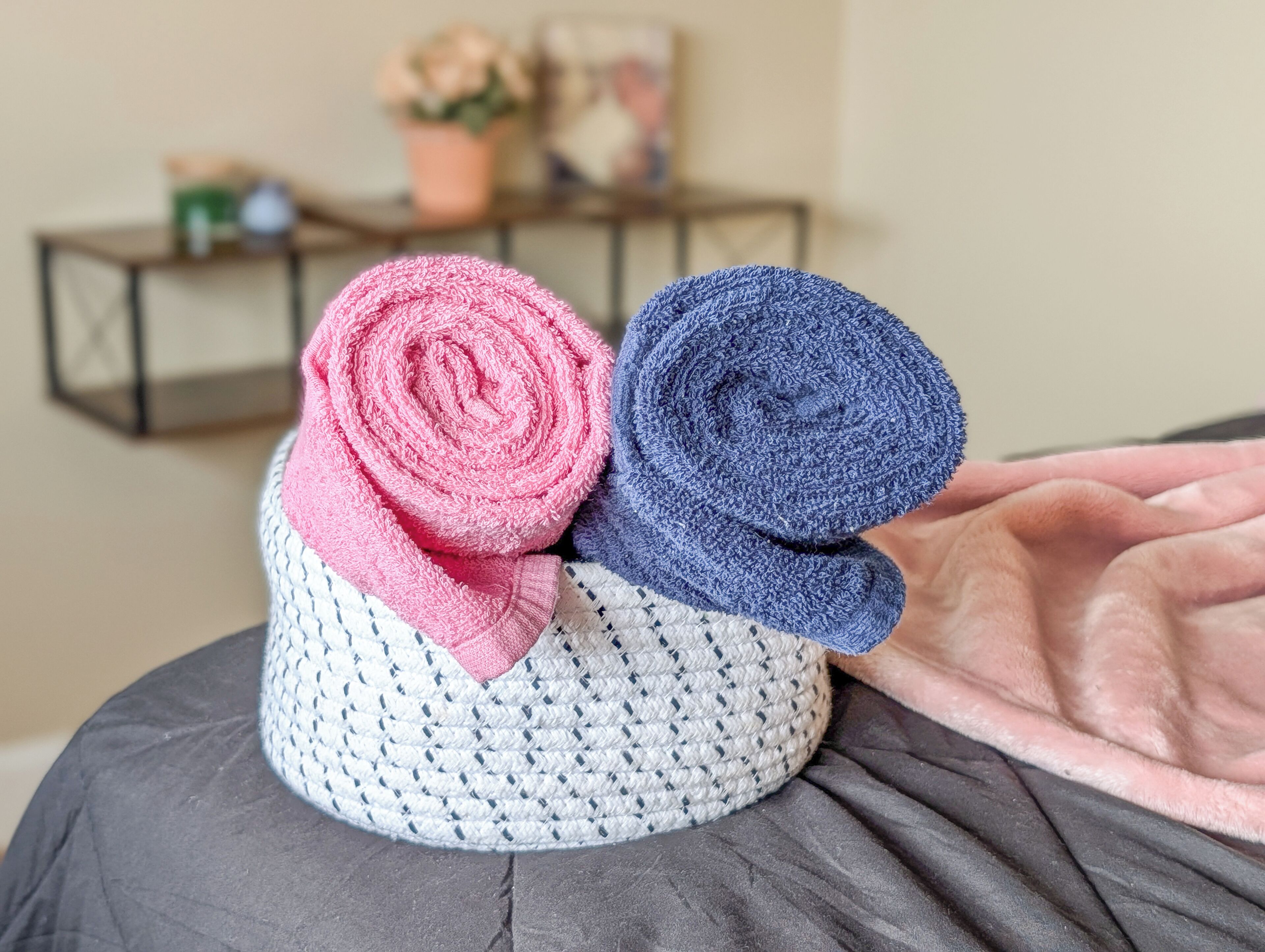 A crocheted hat with a rolled pink and blue interior, placed on a dark surface.