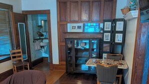 Una sala de estar acogedora con piso de madera, un tapete estampado, un sofá y una mesa de comedor con sillas.