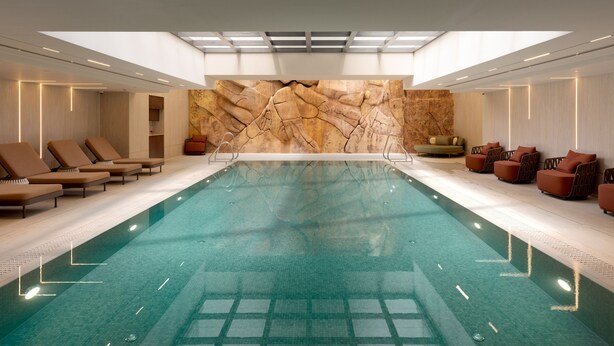 Une piscine avec des chaises longues et un mur d’escalade.