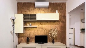 Un salon moderne doté d’un téléviseur à écran plat, d’étagères intégrées, d’un meuble blanc et d’un vase décoratif.