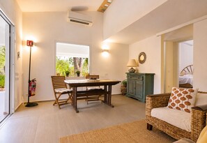 A room with a dining table, chairs, a wicker sofa, a cabinet, a lamp, and a fire extinguisher. - Villa Claudia Relax & Garden – Torre delle Stelle (Torre Delle Stelle (Maracalagonis))