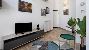 En moderne stue med et fladskærms-tv, vægmonteret aircondition og billeder i rammer på væggene.