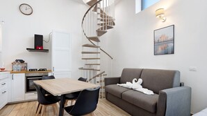 En kompakt bolig med trappegang i spiral, spiseplads, sofa og køkken.